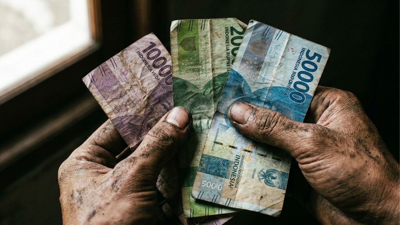 Tangan kotor seorang petani memegang uang kertas lecek hasil panen